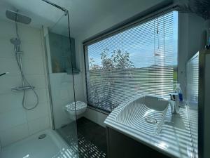 uma casa de banho com um chuveiro, um lavatório e uma janela em Tiny-House No.3 em Lage