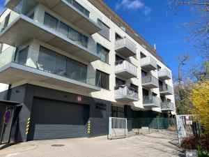 an apartment building with a parking garage in front of it at Forest Park Garden Apartment in Bratislava