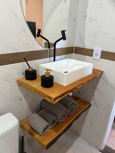 y baño con lavabo y toallas en una estantería de madera. en Aconchegante Suite green, en Niterói