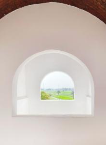 a window in a white wall with a view of a field at Karima House in Luxor