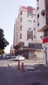 un coche blanco estacionado frente a un edificio en كيان العزيزية للشقق المخدومة - Kayan Al-Azizia Serviced Apartments en Yeda