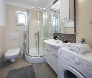 a bathroom with a shower sink and a washing machine at Apartments Vista Bol in Bol +38 photos