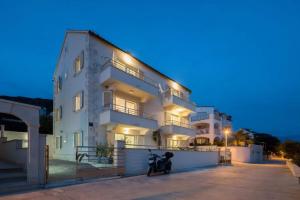 a white building with a scooter parked in front of it at Apartments Vista Bol in Bol