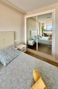sypialnia z łóżkiem i dużym lustrem w obiekcie Luceros Sky w Alicante