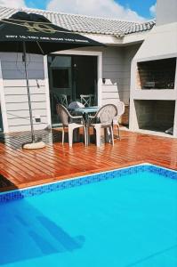 - une table et des chaises avec un parasol à côté de la piscine dans l'établissement Shades of Blue, à Mossel Bay