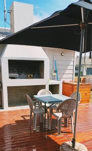 une table, des chaises et un parasol sur une terrasse dans l'établissement Shades of Blue, à Mossel Bay