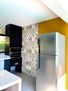 una nevera de acero inoxidable en una cocina con una pared de azulejos en Suítes Por do Sol, en Cabreúva