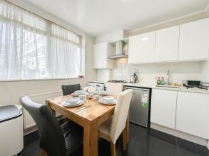 eine Küche mit einem Holztisch und Stühlen in der Unterkunft Modern 3Bedroom 3 Bathroom Apartment with Private Garden- Maida Vale in London