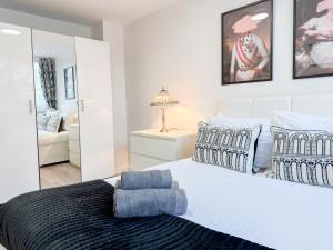 ein Schlafzimmer mit einem großen weißen Bett und einem Spiegel in der Unterkunft Modern 3Bedroom 3 Bathroom Apartment with Private Garden- Maida Vale in London