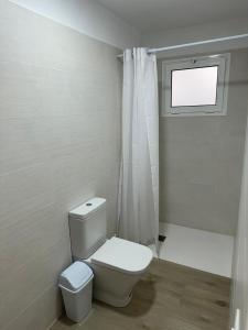 baño blanco con aseo y ventana en Apartamento Chapaleta, en Caleta de Sebo