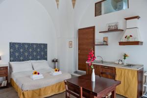 a bedroom with a bed and a table and a kitchen at La Corte Della Luce in Ugento