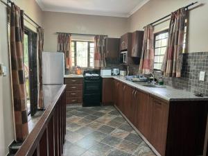 a kitchen with wooden cabinets and a black refrigerator at Manzini chalets 8-9-10-37 in St Lucia