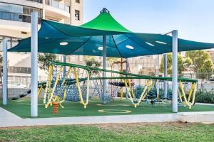 un parque infantil con un dosel azul y verde y columpios en Luxury Flat with Balcony & Ocean View by torohome en Ashdod
