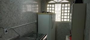a small kitchen with a refrigerator and a window at Riacho Fundo 1 - Riacho Mall in Brasília