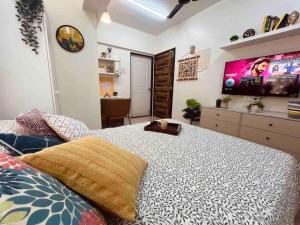 a bedroom with a large bed with a flat screen tv at Dawn - A Spacious Modern Studio in Bandra at Almeida Park by Connekt Homes in Mumbai