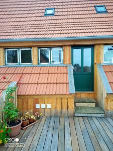 una casa con una puerta verde en una terraza de madera en Gemütliche Premium Öko Ferienwohnung in Resthof, super ausgestattet, keine Handwerker und Monteure, en Sterley