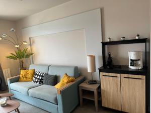 un soggiorno con divano blu e cuscini gialli di appartement vue mer 50m de la plage, WIFI gratuit a Perros-Guirec