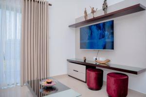 a living room with a tv and two red stools at Apartment -Piliyandala Kahathuduwa in Gonapola