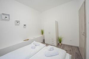 a white room with two white towels on a bed at Perle Vendégház in Kesztölc