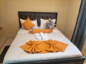 a bed with orange and white sheets and pillows at Weli Glamorous homestay in Naivasha