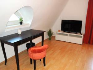 メードリングにあるAppartement Föhrenvillaのデスク、テレビ、椅子が備わる客室です。