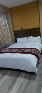 een slaapkamer met een groot bed met witte lakens en kussens bij Lysak Haven Park hotel in Machakos