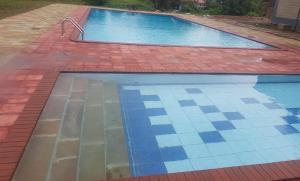 a swimming pool with a brick floor and blue tiles at Lysak Haven Park hotel in Machakos