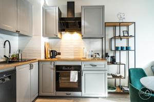 Green Harmony Apartment في سوسنوفييتس: مطبخ فيه دواليب بيضاء وفرن