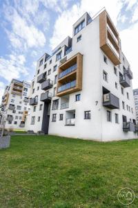 a large white building with windows and a grass field at Green Harmony Apartment in Sosnowiec