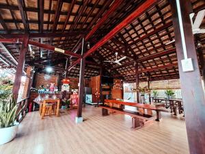 ein Restaurant mit Holztischen und Bänken in einem Zimmer in der Unterkunft HOMESTAY HƯƠNG RỪNG in Tân Phú