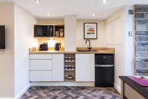 a kitchen with white cabinets and a black refrigerator at The Holt - Ilkley, central location, stylish apartment in Middleton