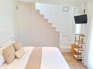 a white bedroom with a bed and a staircase at Casa Portet in Denia