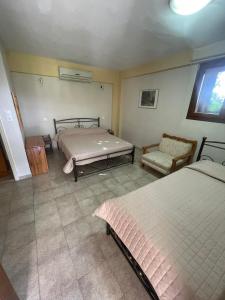 a bedroom with two beds and a couch and a window at Vasilikos Apartments in Paralia Agias Foteinis