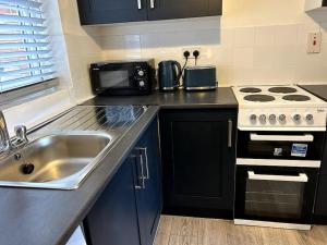 uma cozinha com um lavatório e um fogão em Essex 2 Bedroom Flat near Station with Free Parking em North Ockendon