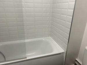 a bathroom with a shower with a white tile wall at Essex 2 Bedroom Flat near Station with Free Parking in North Ockendon