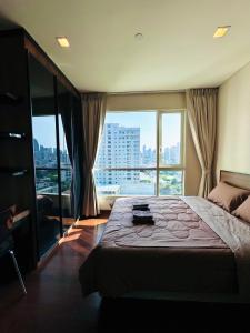 a bedroom with a large bed and a large window at Ivy Thonglor in Khlong Toei