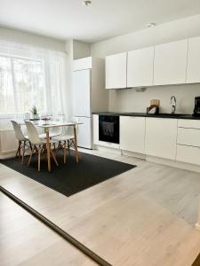 een keuken met witte kasten en een tafel en stoelen bij Täysin remontoitu kaksio. Ilmainen pysäköinti! in Turku