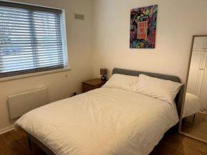 um quarto com uma cama branca e uma fotografia na parede em Essex 2 Bedroom Flat near Station with Free Parking em North Ockendon