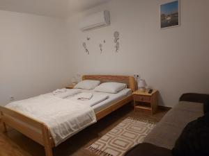 1 dormitorio con 1 cama con sábanas blancas y mesita de noche en Potyka Apartman, en Tiszafüred