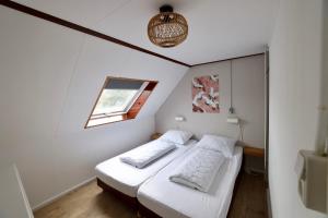 Habitación pequeña con 2 camas y ventana en Dubbelduyn vakantie boerderij Callantsoog, en Callantsoog