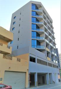 a tall building with a parking garage in front of it at Infinity Juffair Suites in Juffair