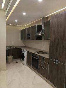 a kitchen with wooden cabinets and a washer and dryer at Infinity Juffair Suites in Juffair