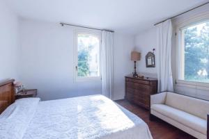 una camera da letto con un letto, una sedia e due finestre di Palazzo Bonfiglioli a Lorenzatico