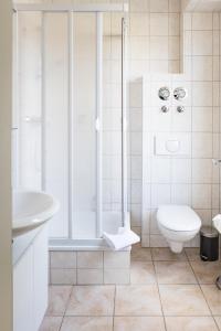 a white bathroom with a shower and a toilet at Villa Aida in Ahlbeck