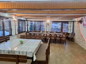 a dining room with tables and chairs and windows at Perla Guest House in Dospat