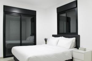 a white bed with a black headboard and white pillows at Penthouse #47 By Hashdera Eilat in Eilat