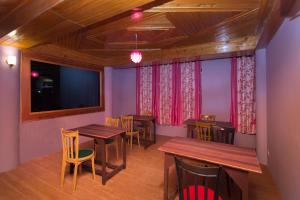 een restaurant met houten tafels en stoelen en een flatscreen-tv bij OYO Flagship Balaji Guest House in Shillong