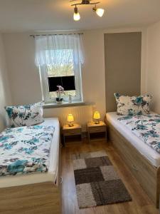 two beds in a room with a window and two lamps at Ferienwohnung Streit in Kurort Gohrisch