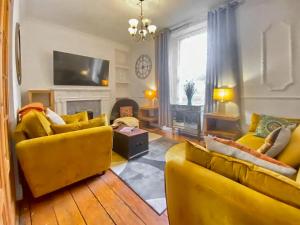 uma sala de estar com dois sofás amarelos e uma televisão em Four-tunes em Torquay