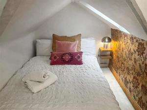 uma cama branca com almofadas e uma toalha em Four-tunes em Torquay